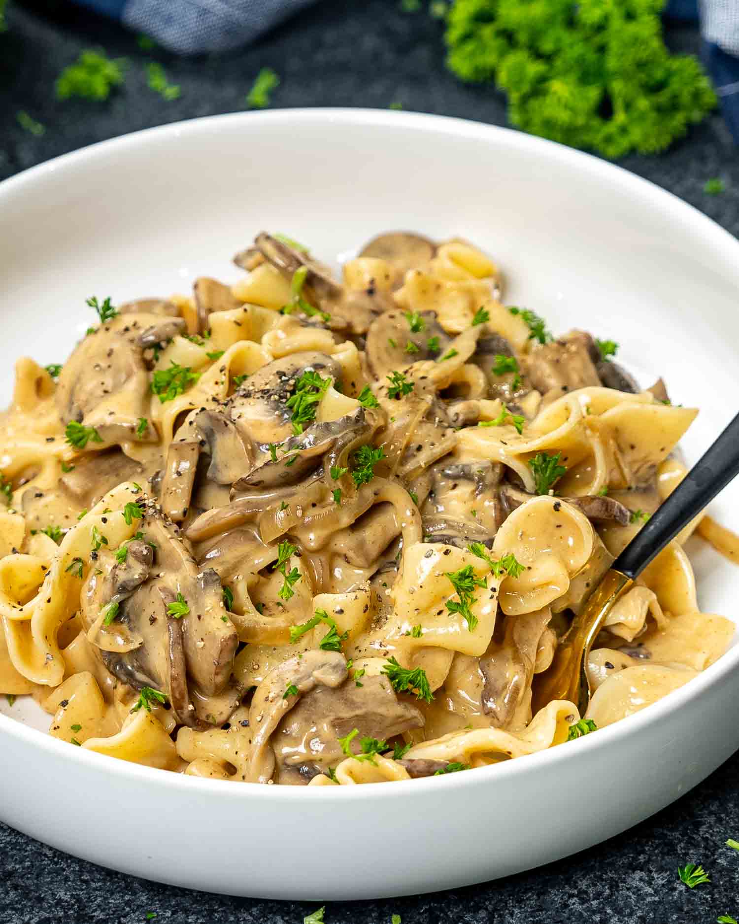 a serving of mushroom stroganoff in a white bowl garnished with parsley.