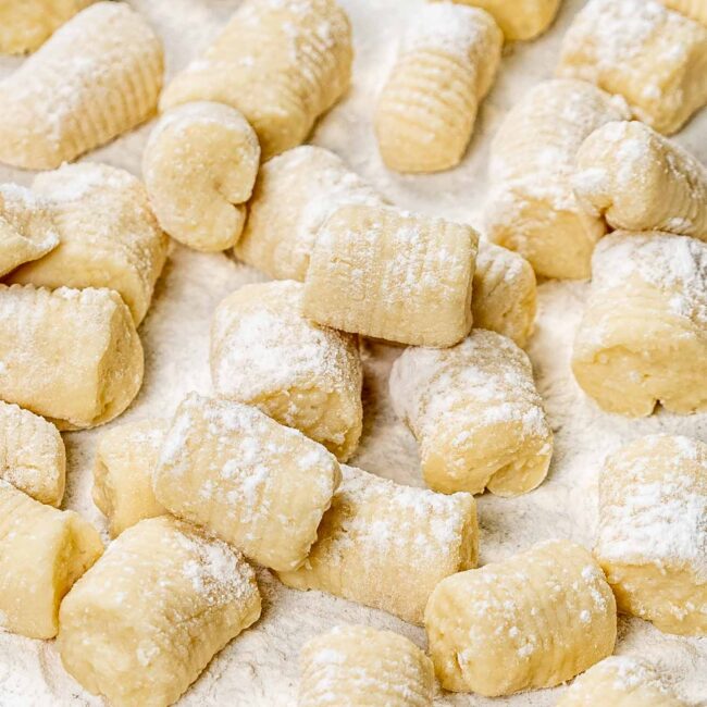 freshly made gnocchi coated with flour on a counter.
