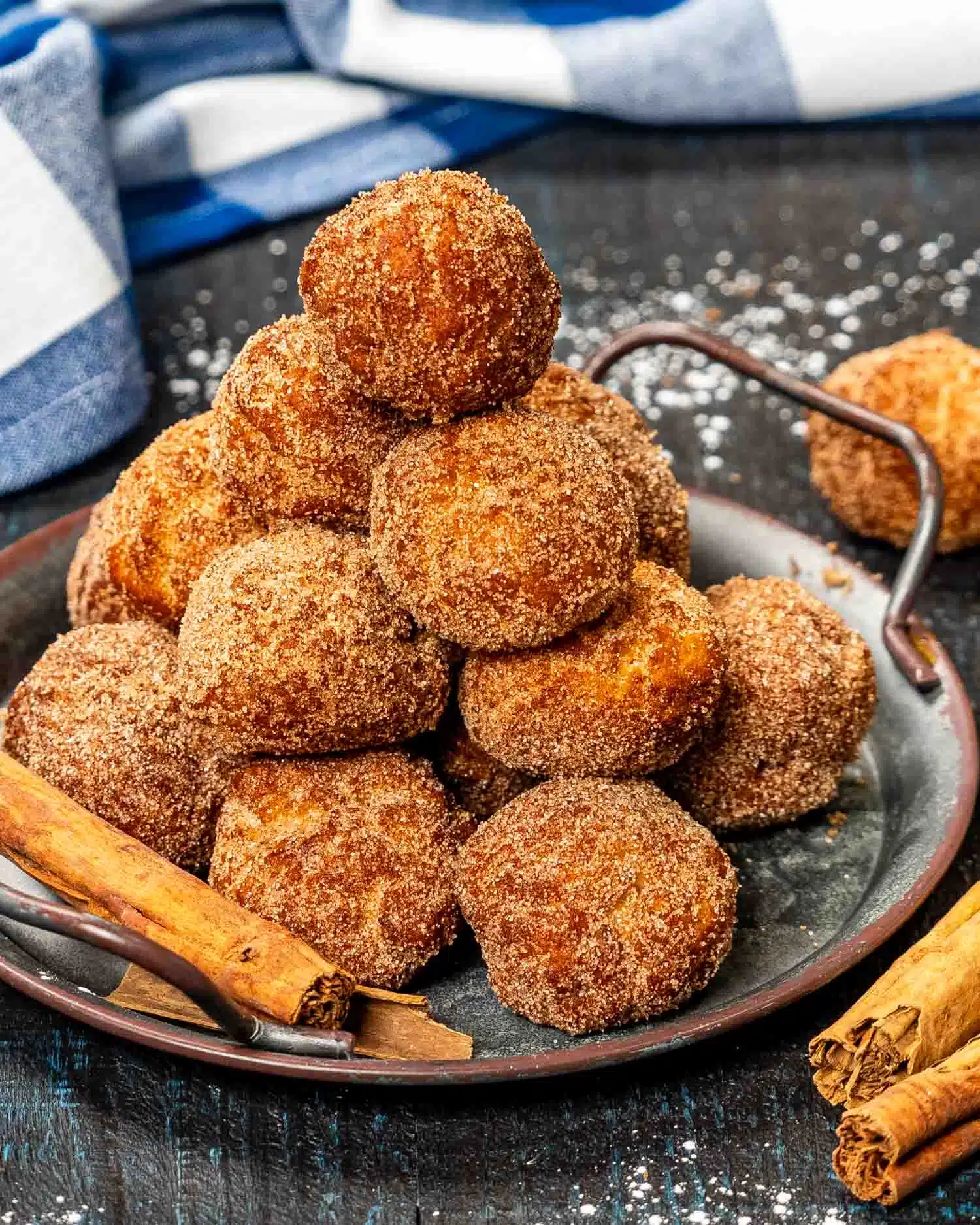 a metal plate with stacked cinnamon sugar donuts holes.