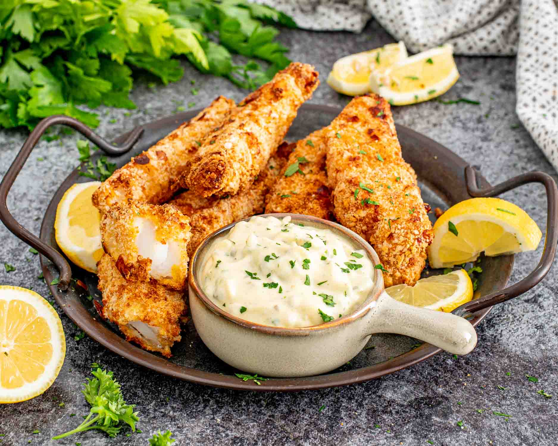 air fried fish sticks on a platter with a bowl with tartar sauce in it.