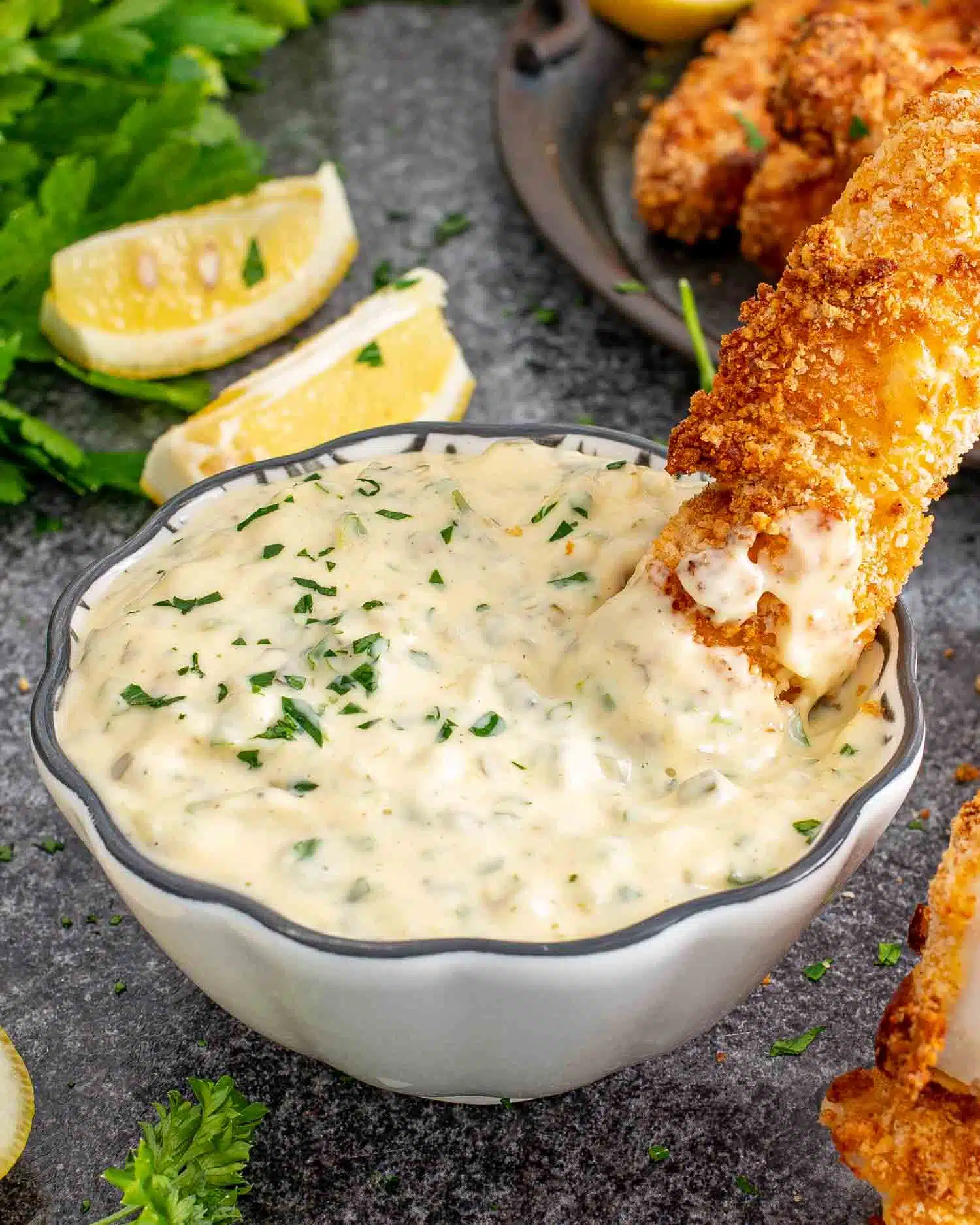 tartar sauce in a little dish with a fish stick in it.