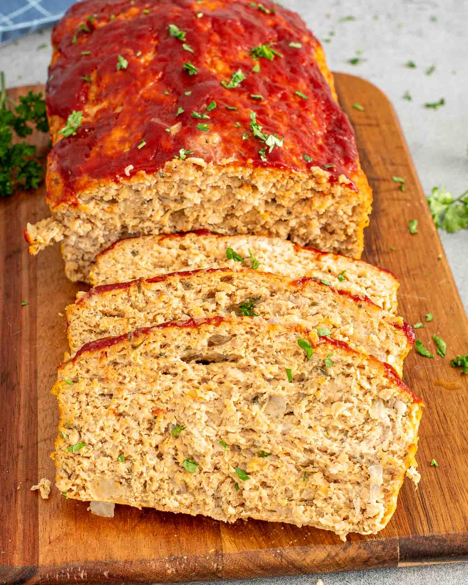 sliced up chicken meatloaf on a cutting board garnished with parsley.