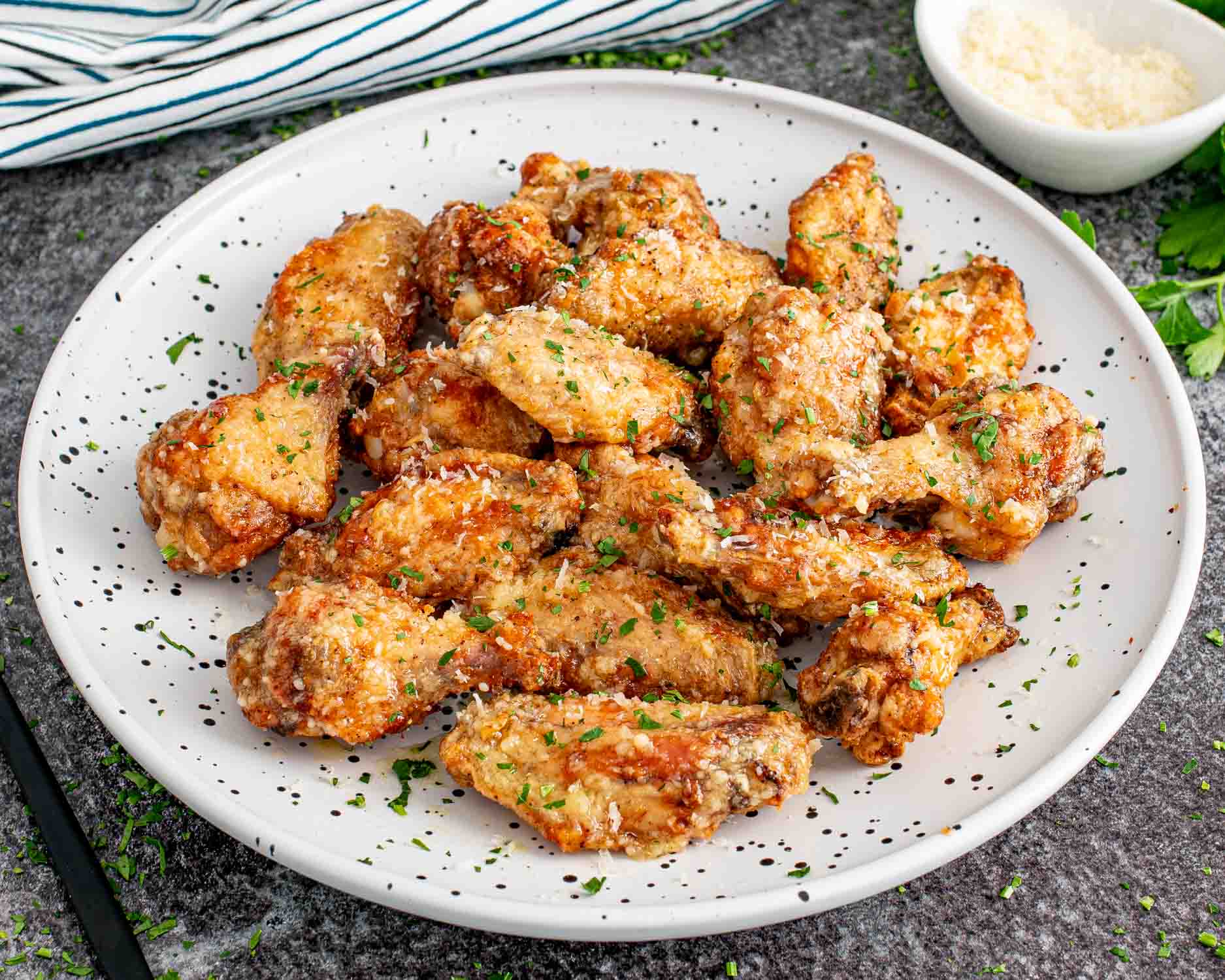 freshly made garlic parmesan wings on a white plate.