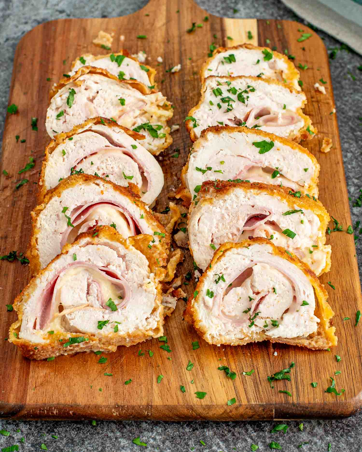 two pieces of chicken cordon bleu sliced up on a cutting board.