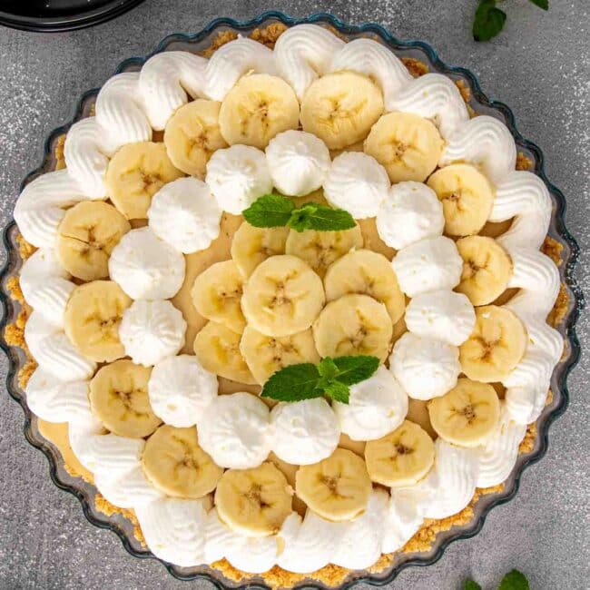 a banana cream ie in a pie plate garnished with some fresh mint.