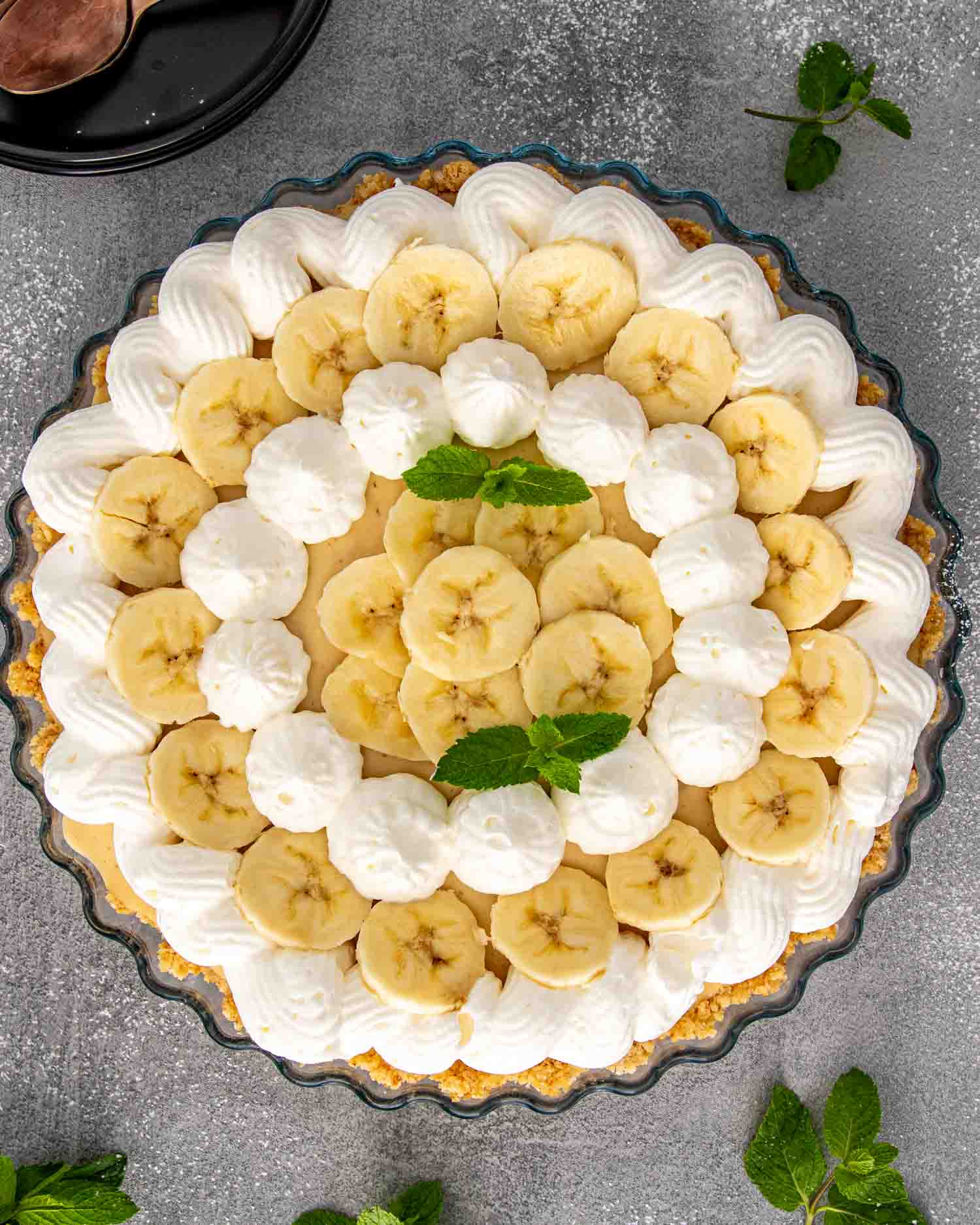 a banana cream ie in a pie plate garnished with some fresh mint.