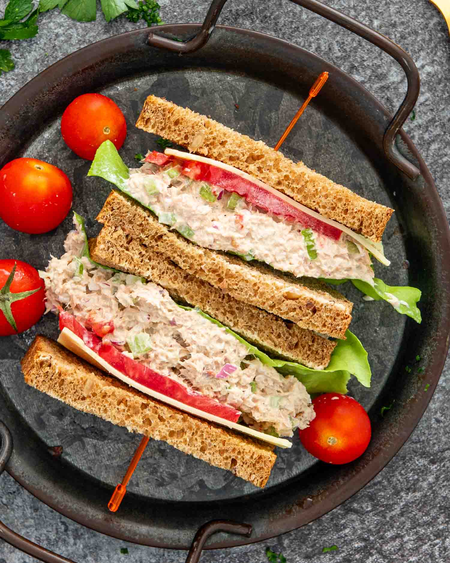 a tuna salad sandwich cut in half on a plate.