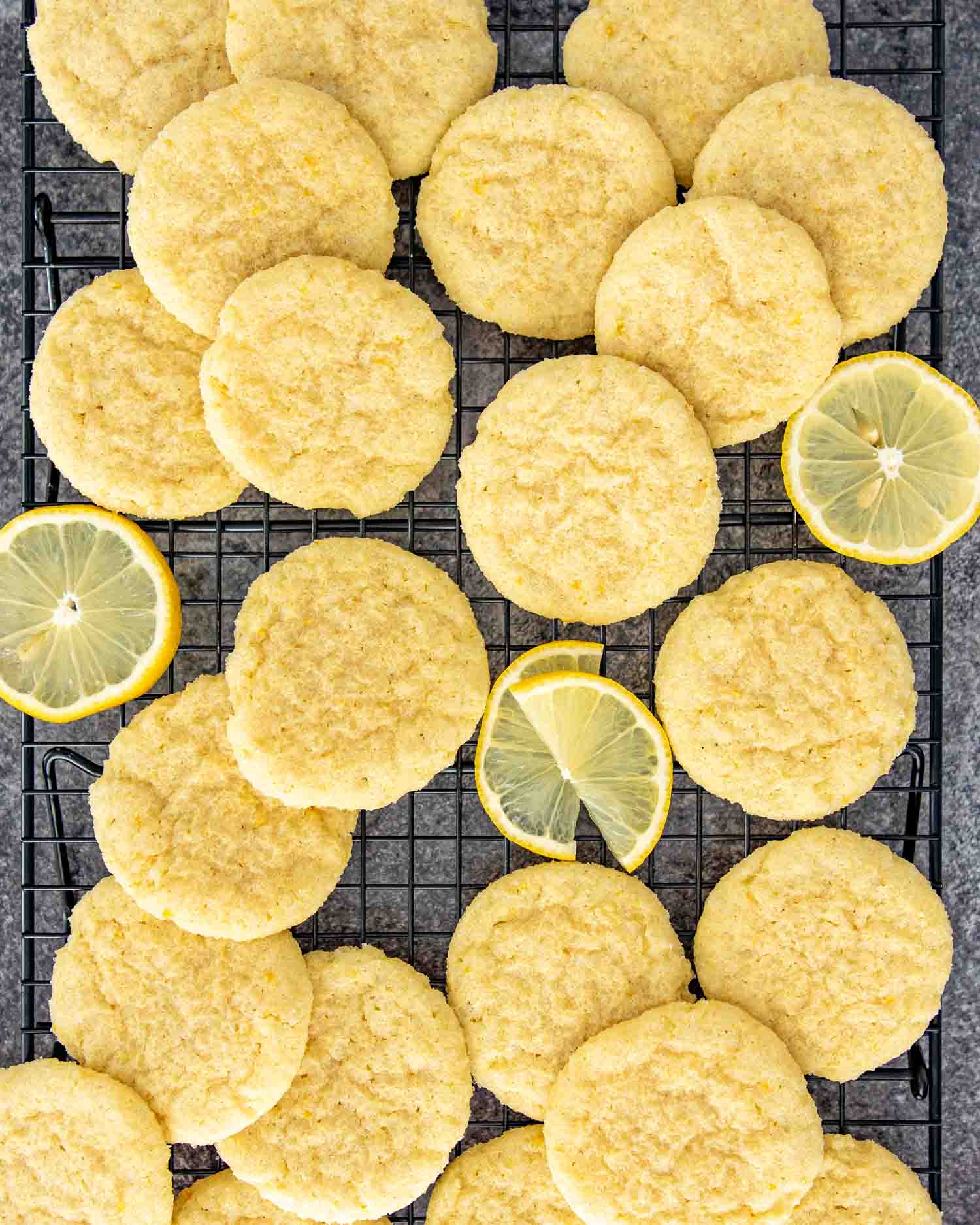 lemon sugar cookies cooling on a black cooling rack.