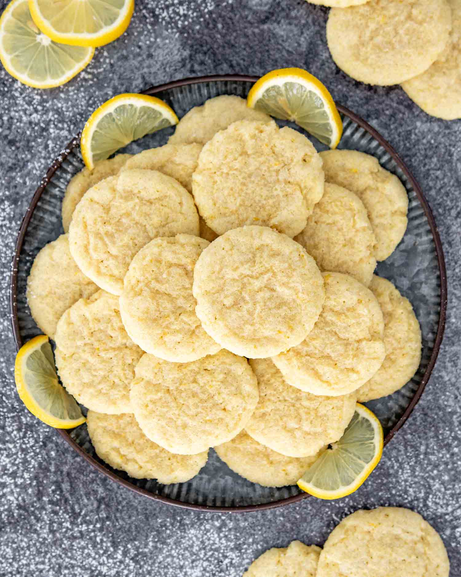 a stack of freshly baked lemon sugar cookies on a black plate.