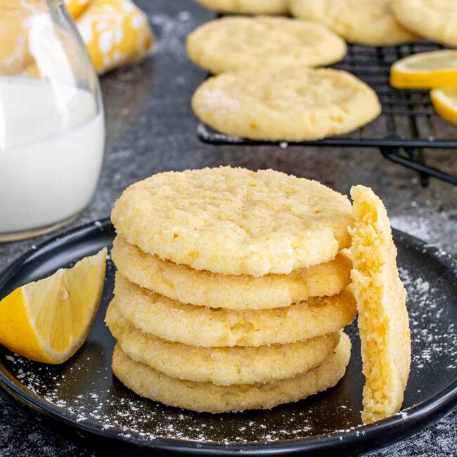 a stack of freshly baked lemon sugar cookies on a black plate.