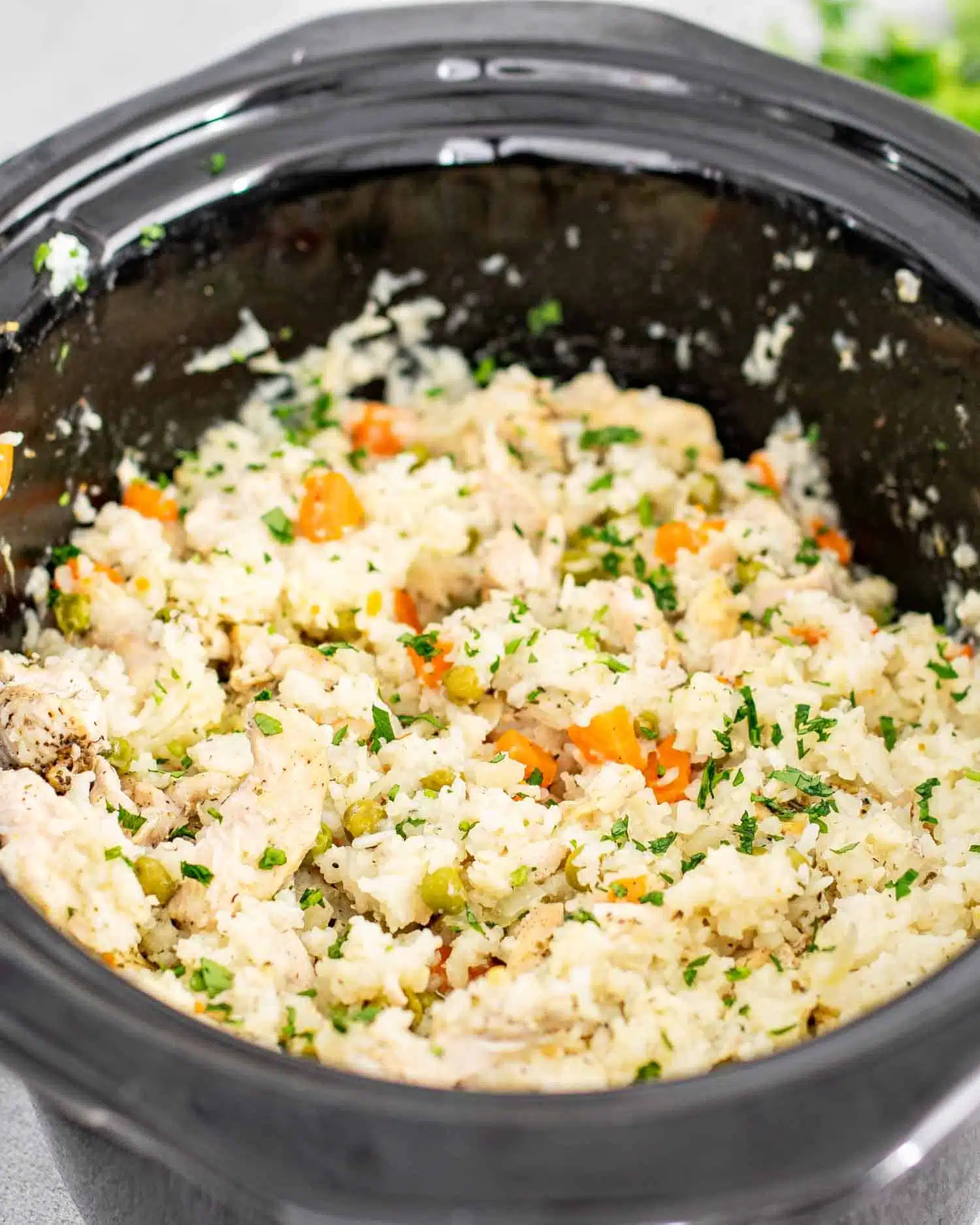 chicken and rice in a crockpot garnished with a bit of parsley.
