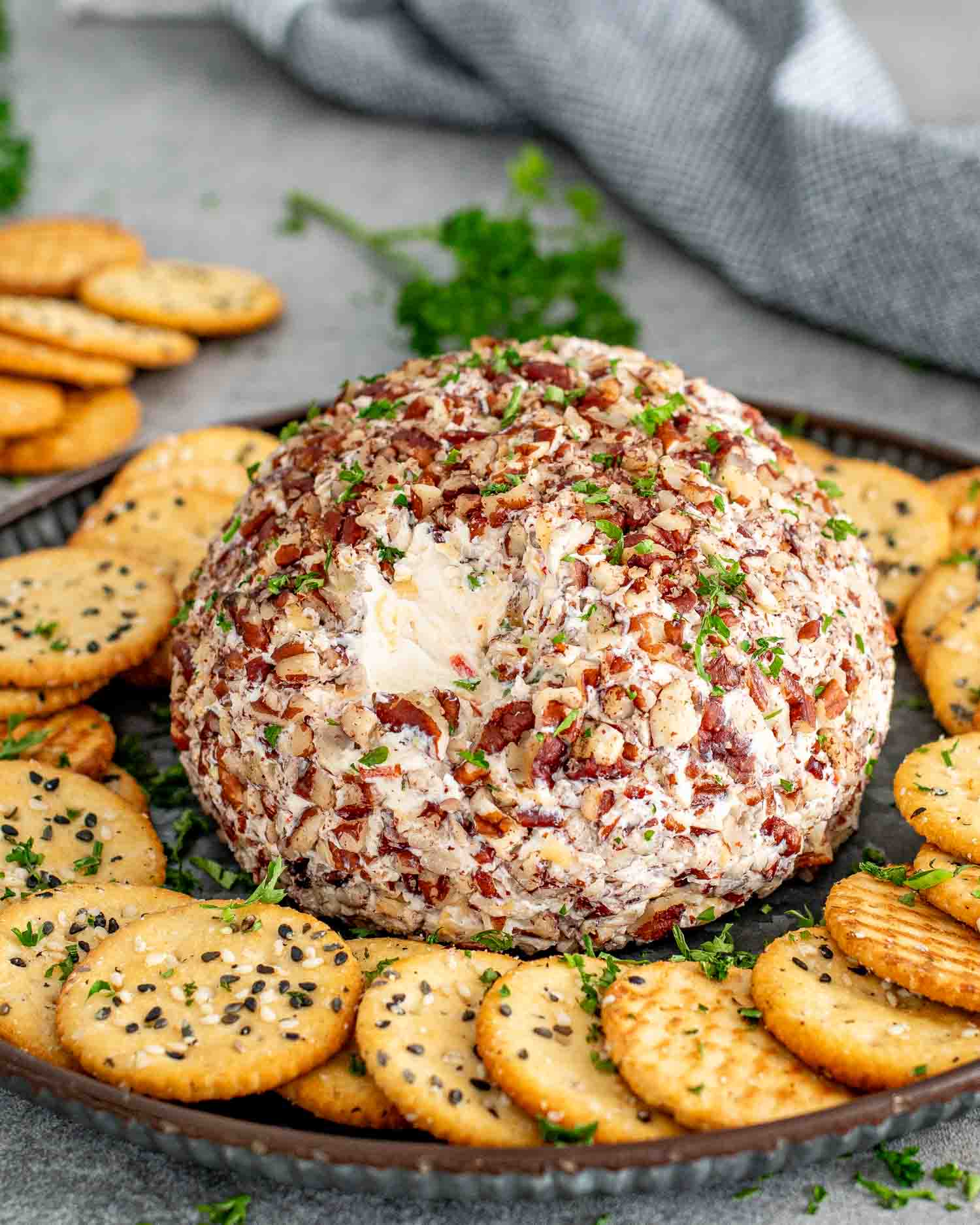 a cheese ball on a plate surrounded by crackers.