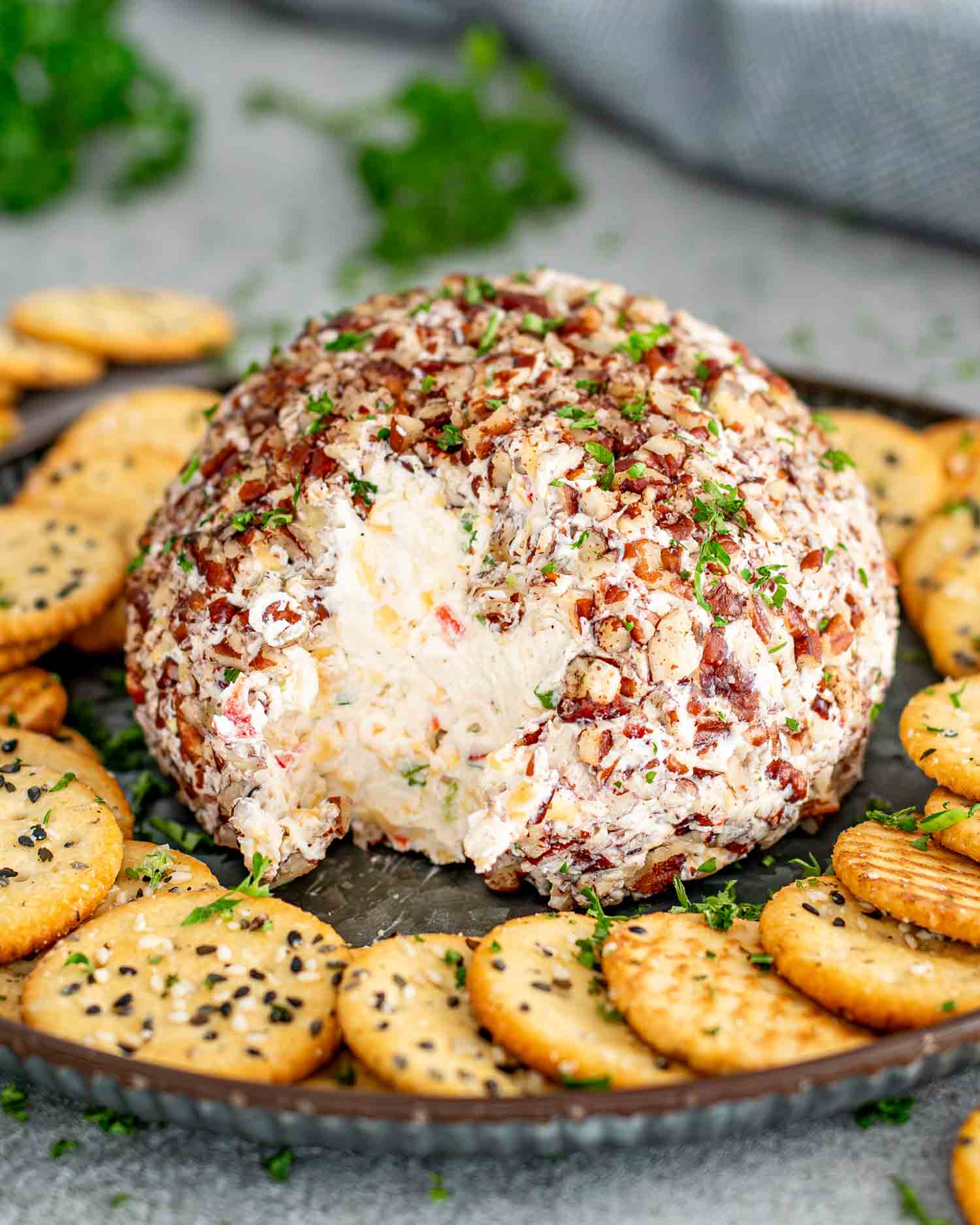 a cheese ball on a plate surrounded by crackers.