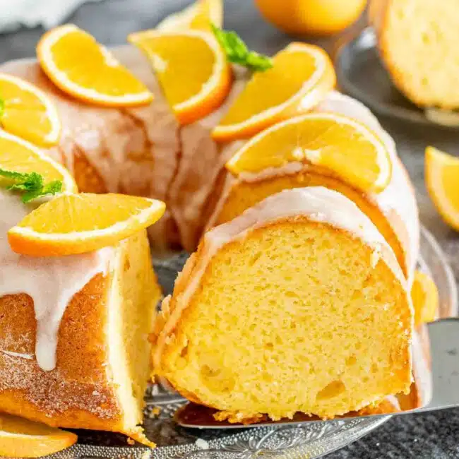 a freshly baked harvey wallbanger cake garnished with orange slices on a cake platter.