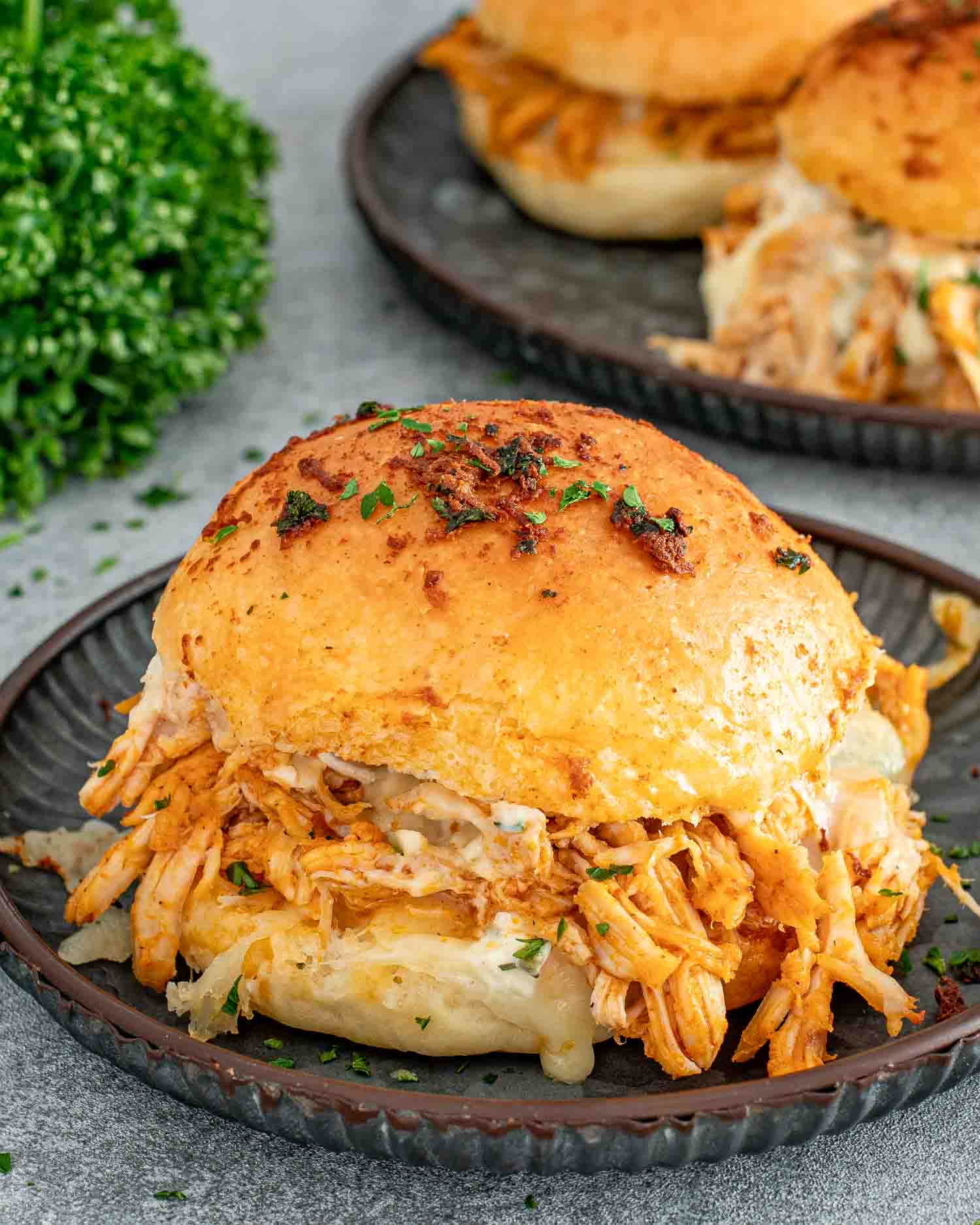 a golden-brown buffalo chicken slider freshly baked on a metal plate.