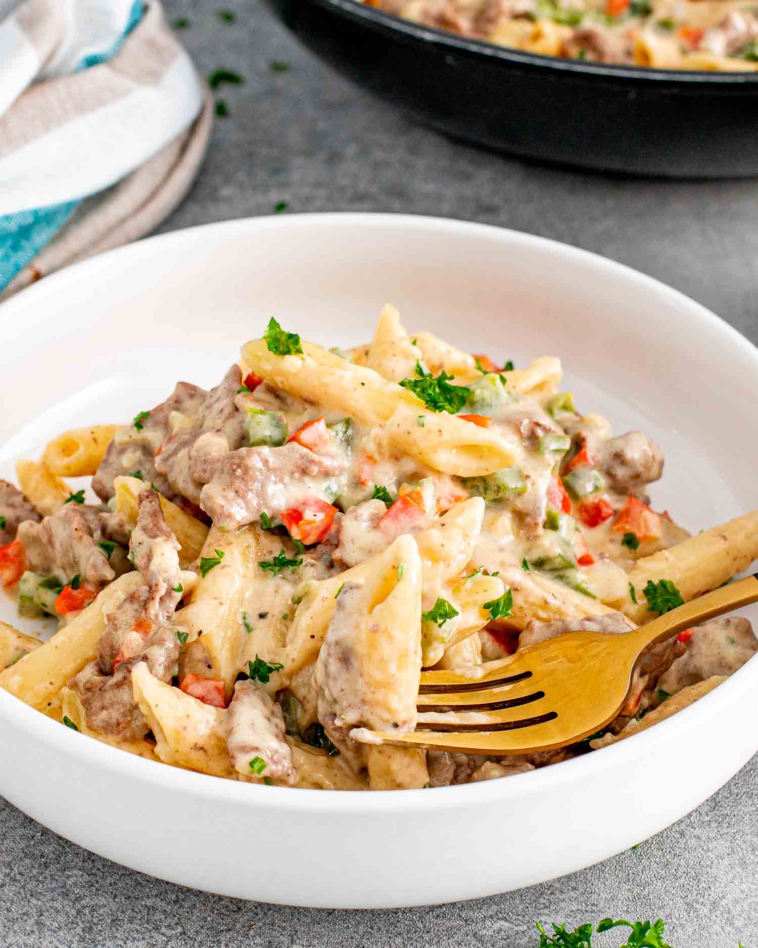 a serving of creamy dreamy cheesesteak pasta in a white bowl.