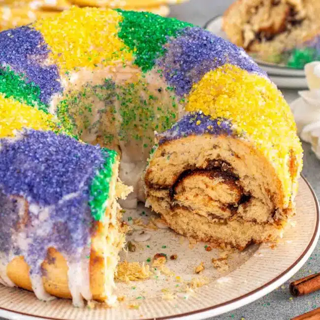 a gorgeous mardis gras king cake on a plate beautifully decorated.