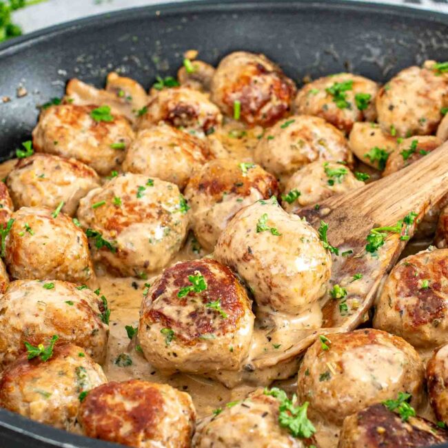 freshly made creamy mushroom chicken meatballs in a skillet garnished with parsley.