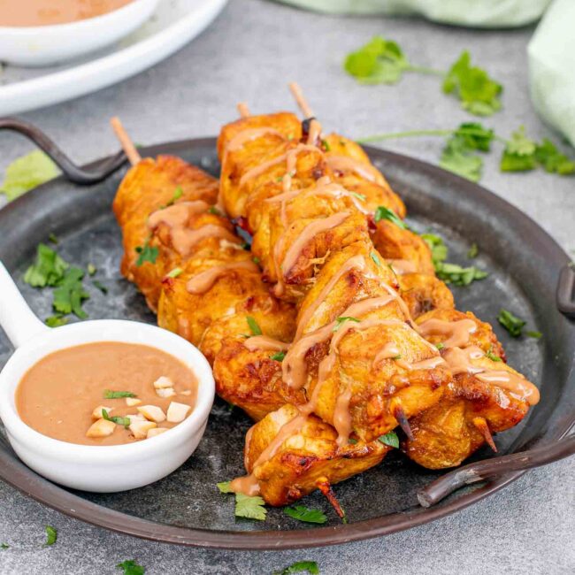a serving of chicken satay with peanut sauce on a plate.