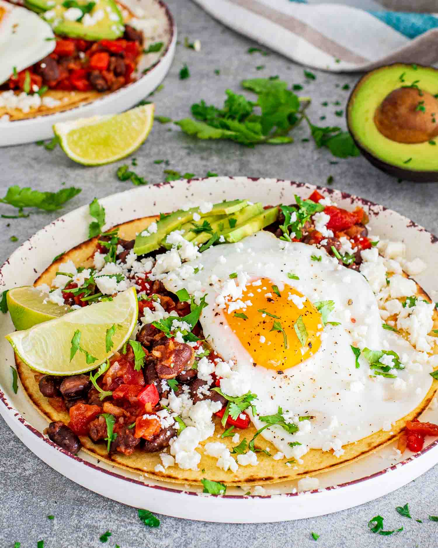 a gorgeous plate of huevos rancheros garnished with queso fresco, sliced avocado and lime wedges.
