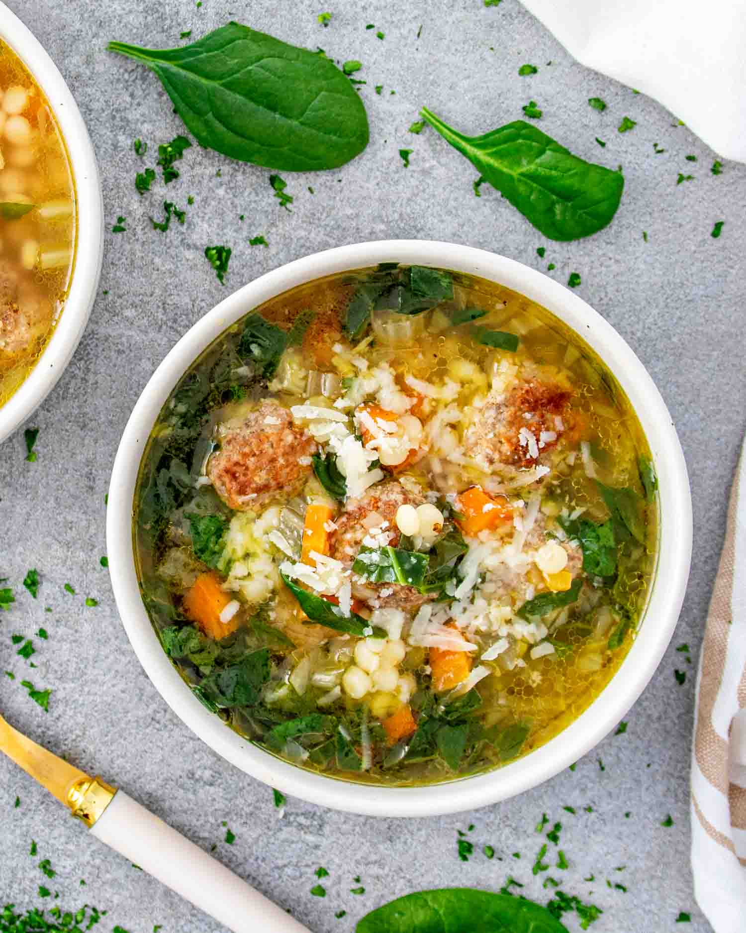 a serving of italian wedding soup in a white bowl.