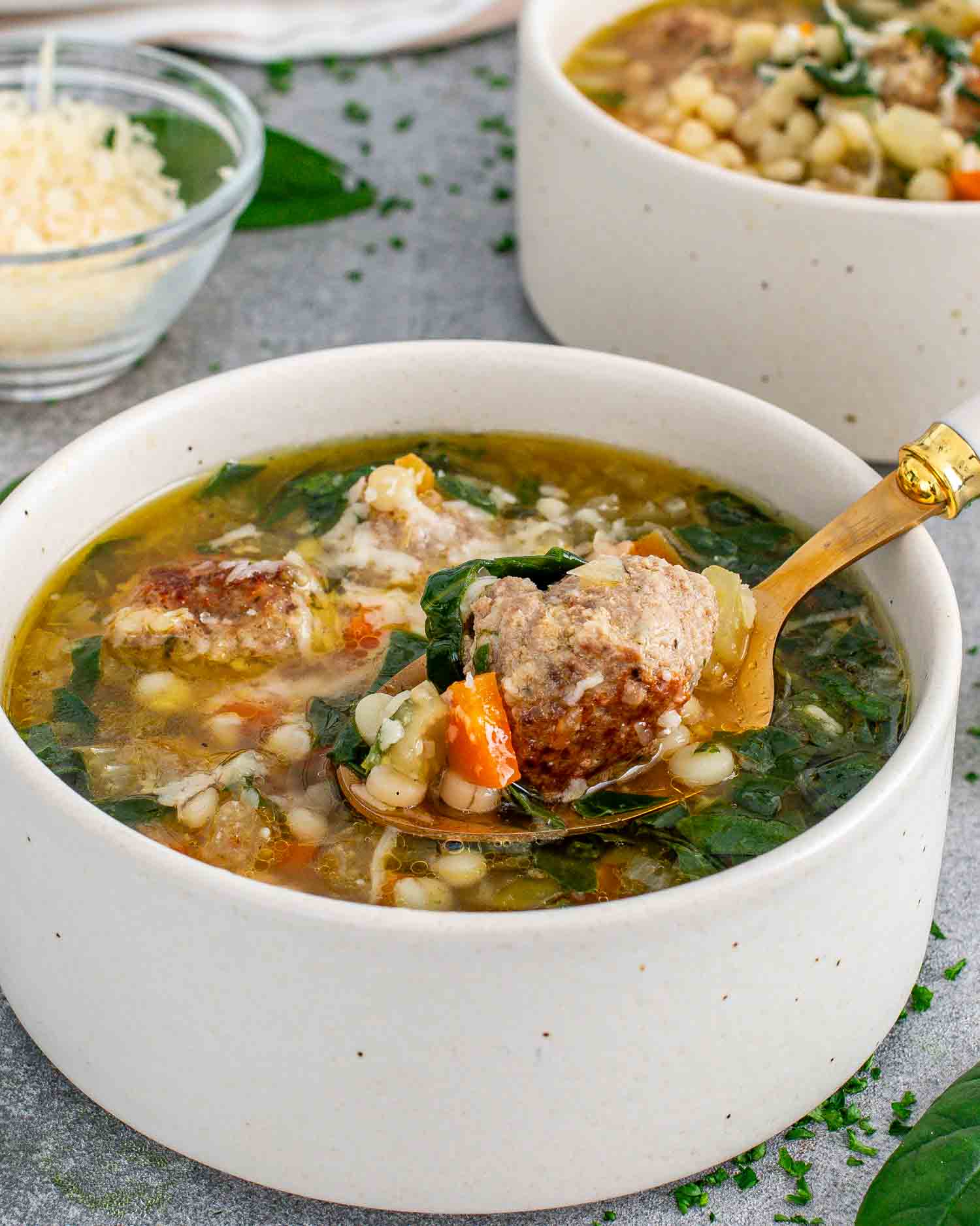 a serving of italian wedding soup in a white bowl.
