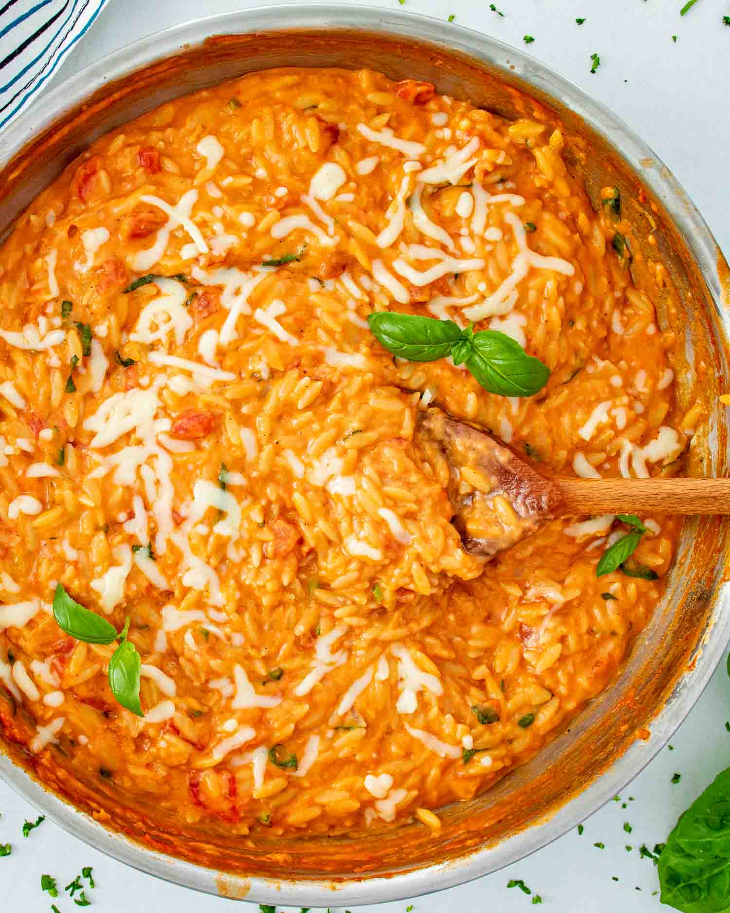 freshly made cheesy tomato basil orzo in a stainless steel skillet.