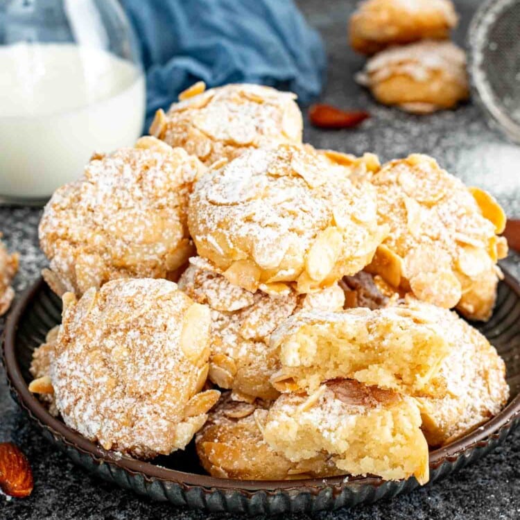 a plateful of freshly made italian almond cookies dusted with a bit of powdered sugar.