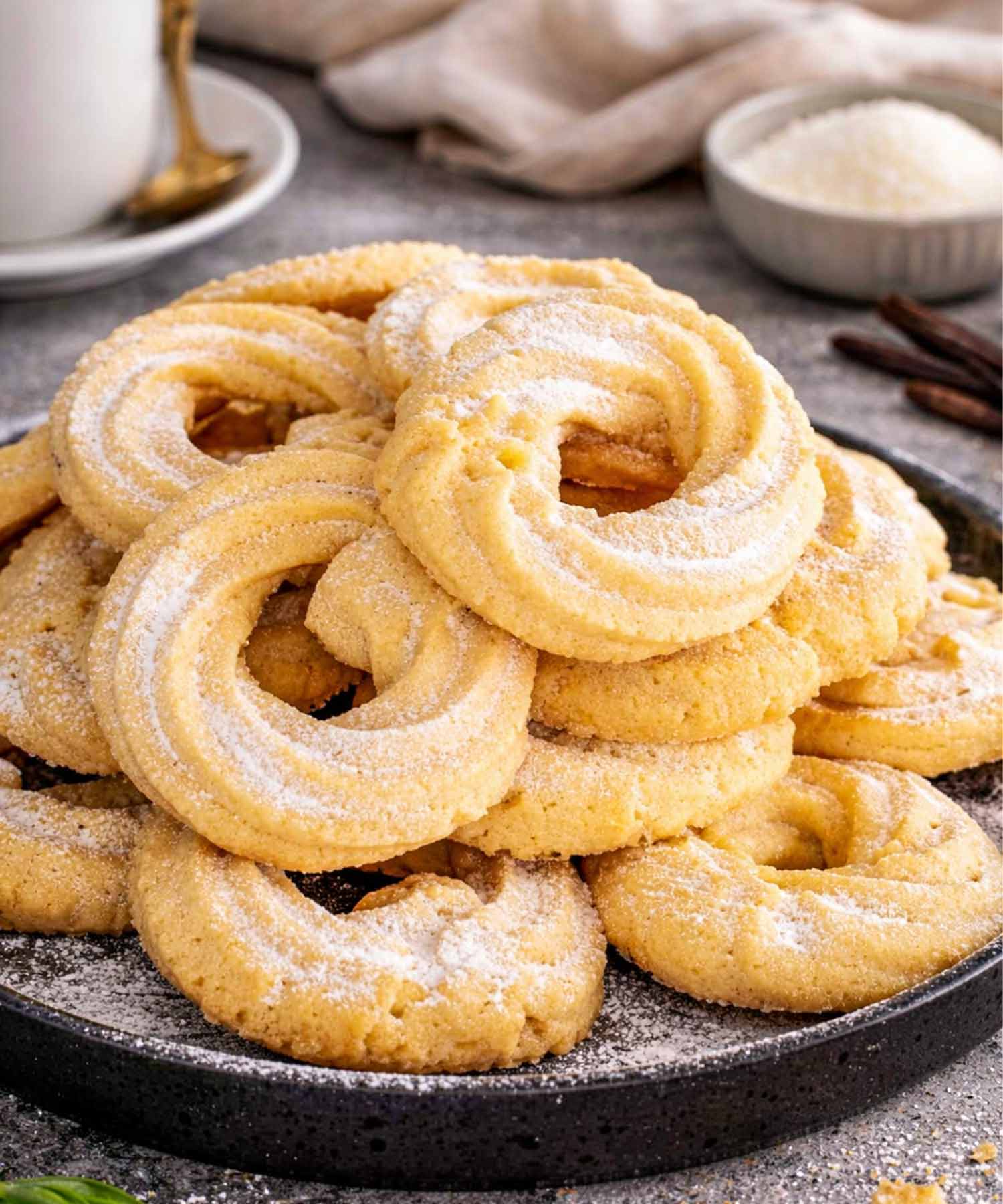 freshly made danish butter cookies dusted with powdered sugar on a plate.