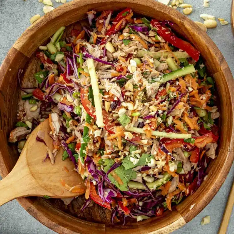 fresh asian tuna salad in a wooden bowl with a wooden spoon inside.