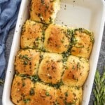 Golden garlic herb pull apart rolls in a baking dish, brushed with melted butter and fresh herbs for a soft, fluffy texture.