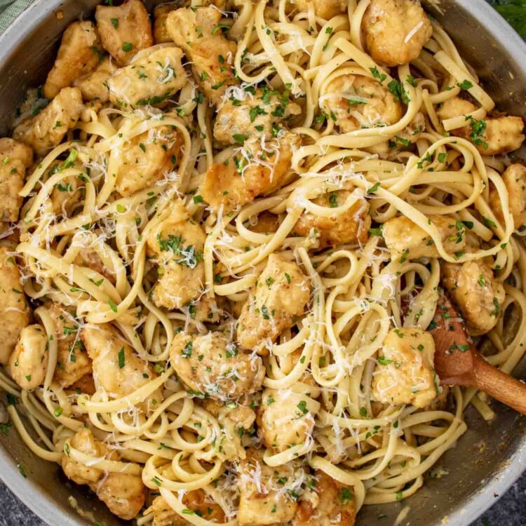 Chicken scampi cooked in a large skillet with golden chicken, linguine, Parmesan cheese, and garlic lemon butter sauce.