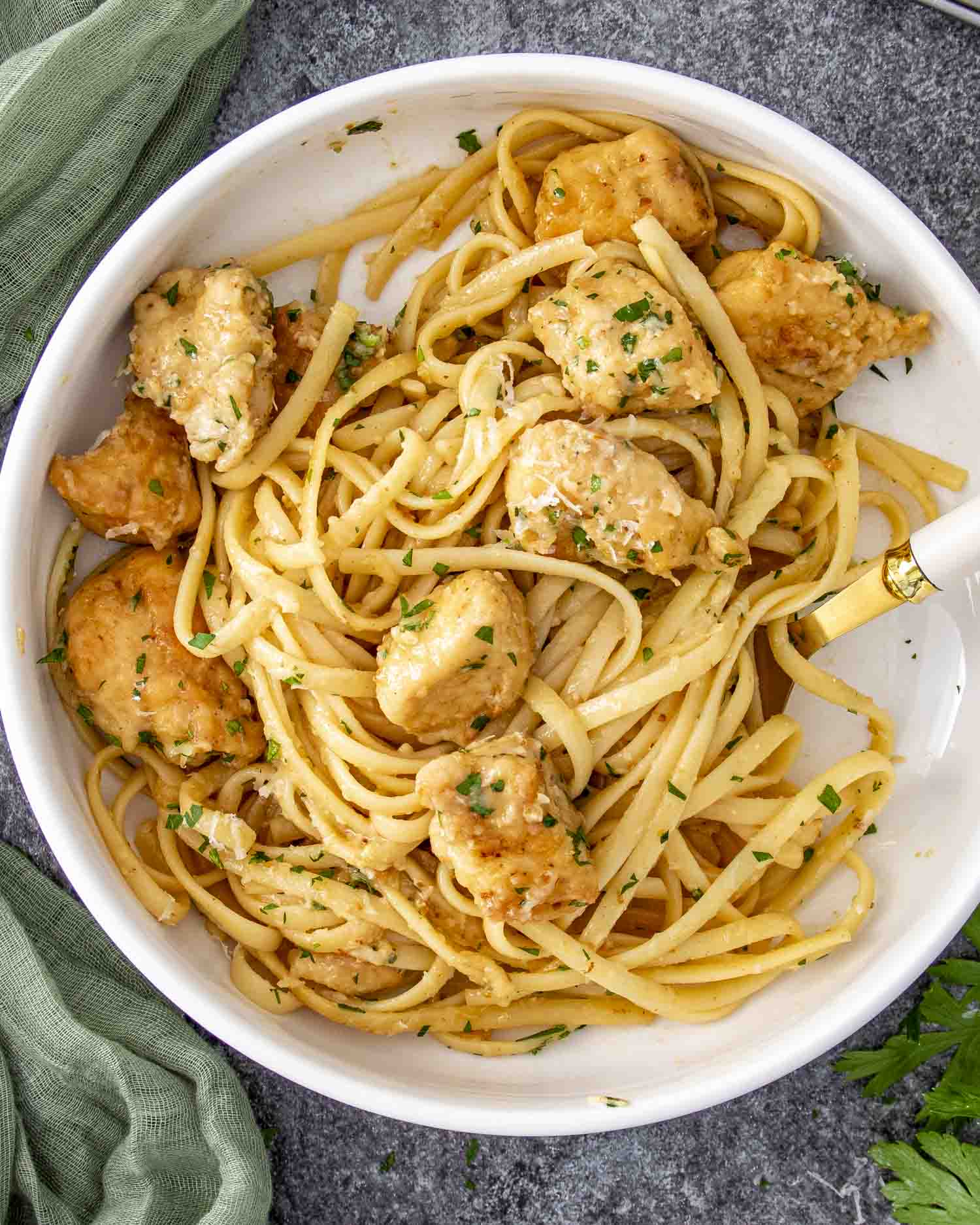 Chicken scampi with tender chicken pieces and linguine tossed in a buttery garlic lemon sauce, garnished with parsley.