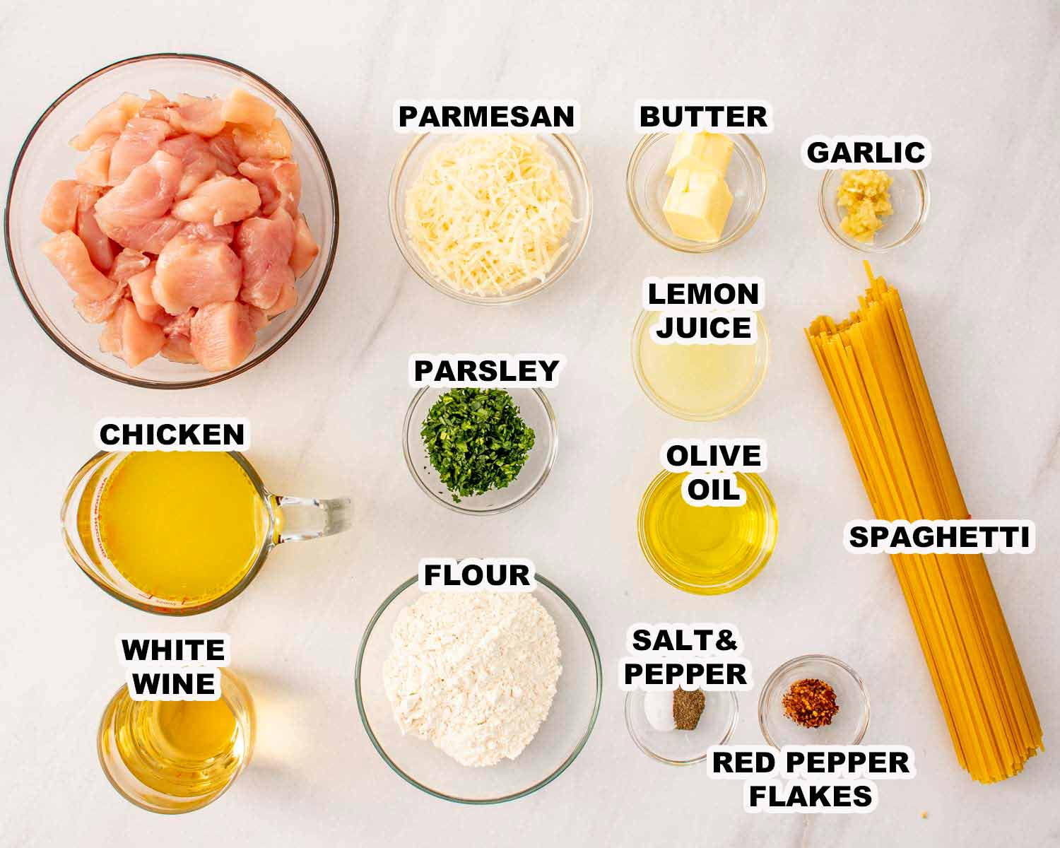 Ingredients for chicken scampi including chicken, spaghetti, garlic, lemon juice, white wine, Parmesan, parsley, butter, and olive oil.