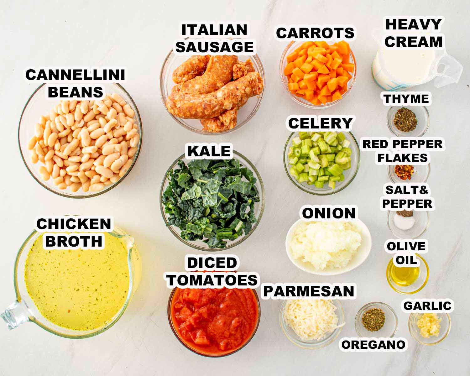 Ingredients for sausage and white bean soup including Italian sausage, cannellini beans, kale, vegetables, herbs, broth, and cream.