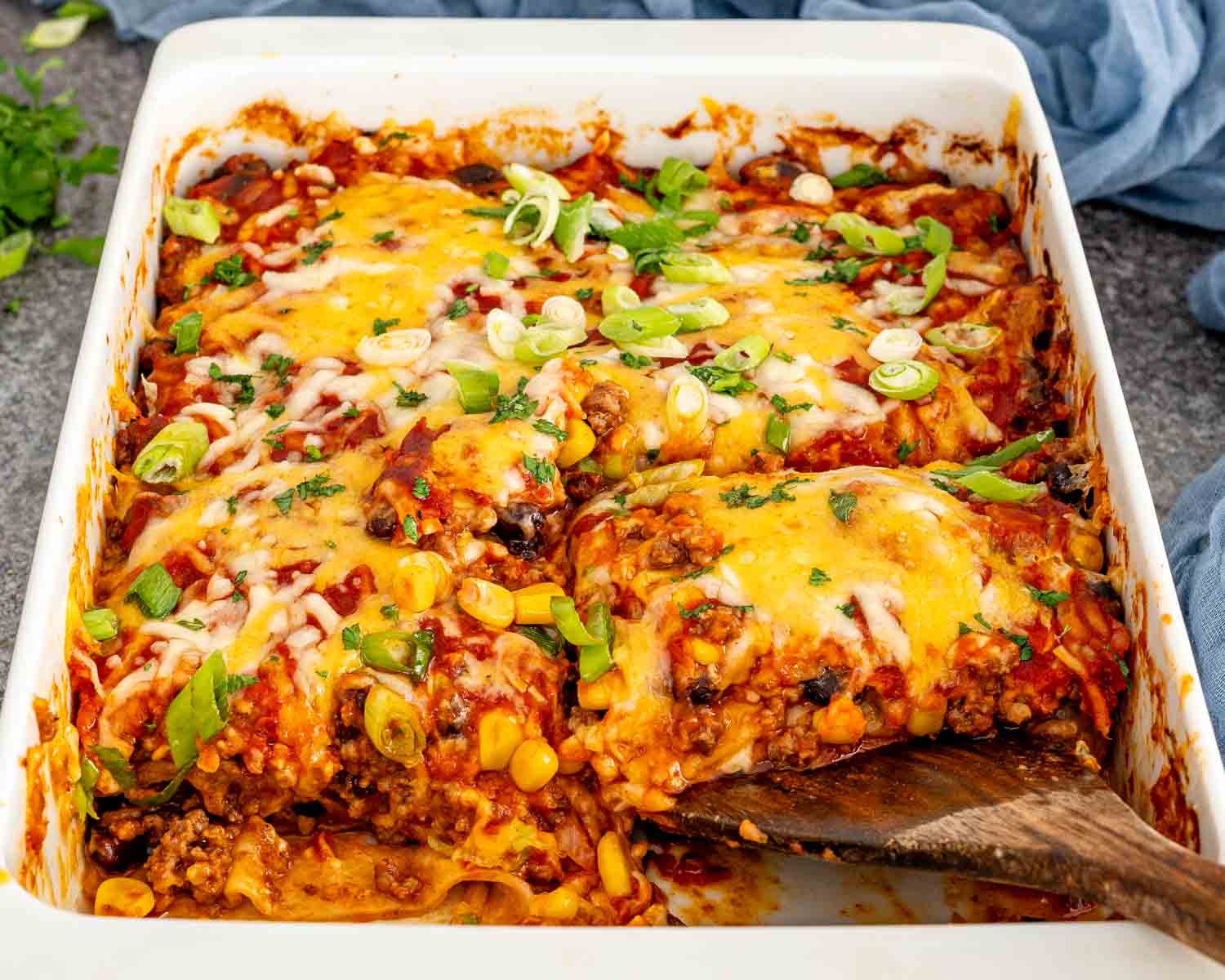 Cheesy beef enchilada casserole scoop revealing corn, black beans, and saucy ground beef inside the baked layers.