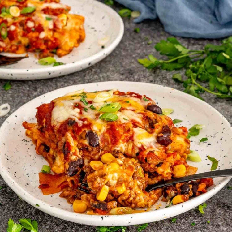 Close-up of beef enchilada casserole showing layers of seasoned ground beef, enchilada sauce, tortillas, and cheese.