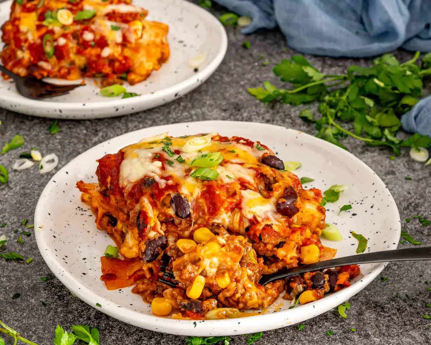Close-up of beef enchilada casserole showing layers of seasoned ground beef, enchilada sauce, tortillas, and cheese.