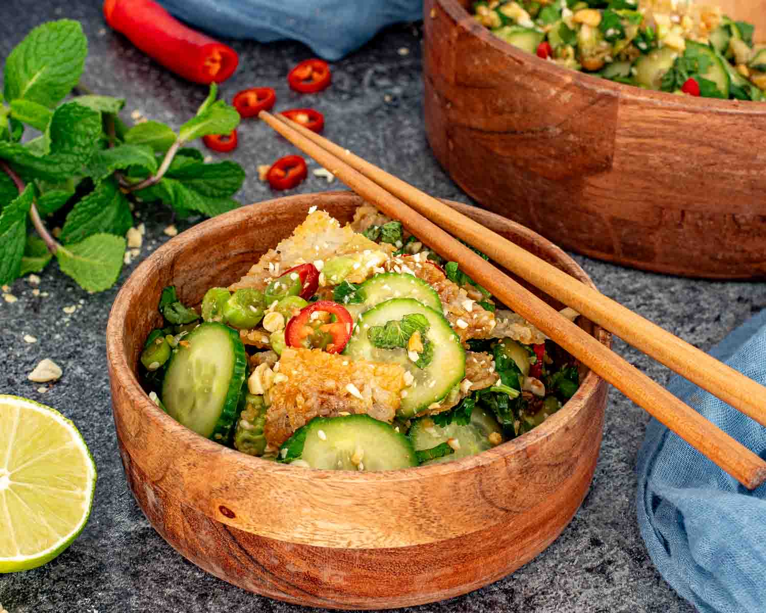 Crispy rice cucumber salad served in a wooden bowl with chopsticks, showing crunchy rice, cucumbers, and herbs.