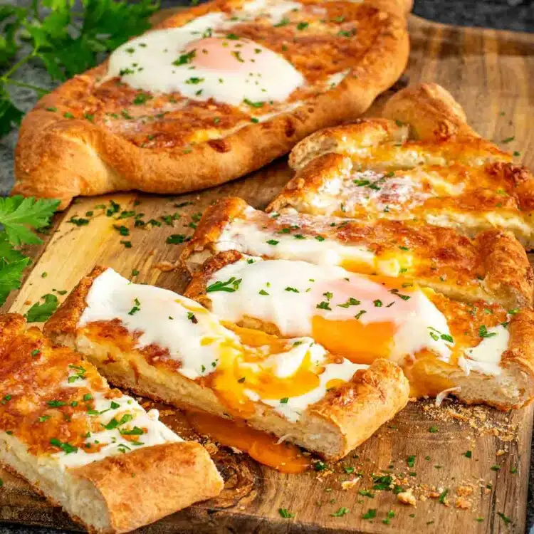 Khachapuri Georgian cheese bread sliced open with golden egg yolk flowing over melted cheese center.