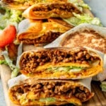 Stacked Taco Bell Crunchwrap Supreme copycat wraps on a wooden board with visible crunchy tostada and seasoned beef layers.