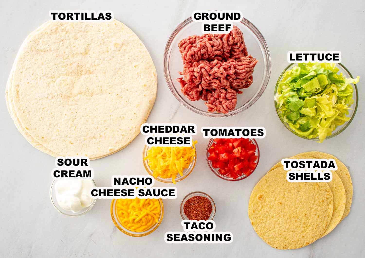 Ingredients for Taco Bell Crunchwrap Supreme copycat including tortillas, ground beef, lettuce, cheese, tomatoes, tostada shells, and sauce.