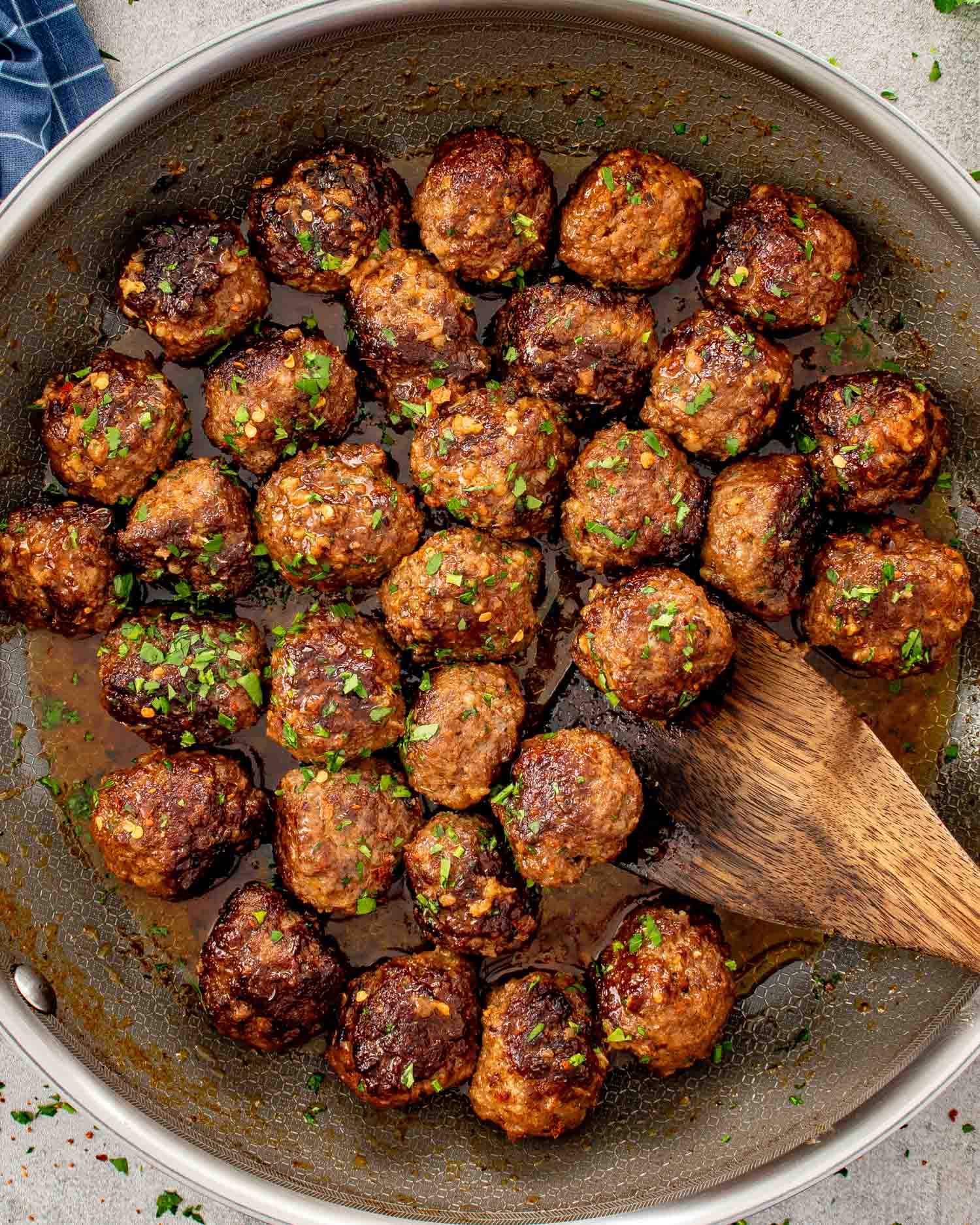Golden brown beef meatballs seared in a skillet with crispy edges, chopped parsley, and pan juices pooling underneath.