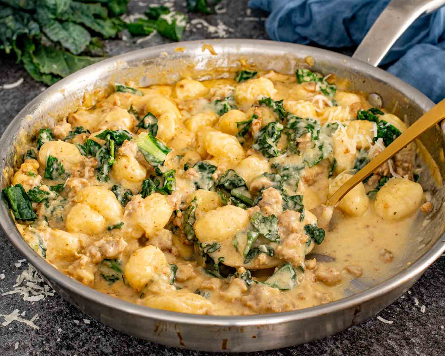 Large skillet filled with creamy gnocchi, Italian sausage, and kale in a rich Parmesan cream sauce.