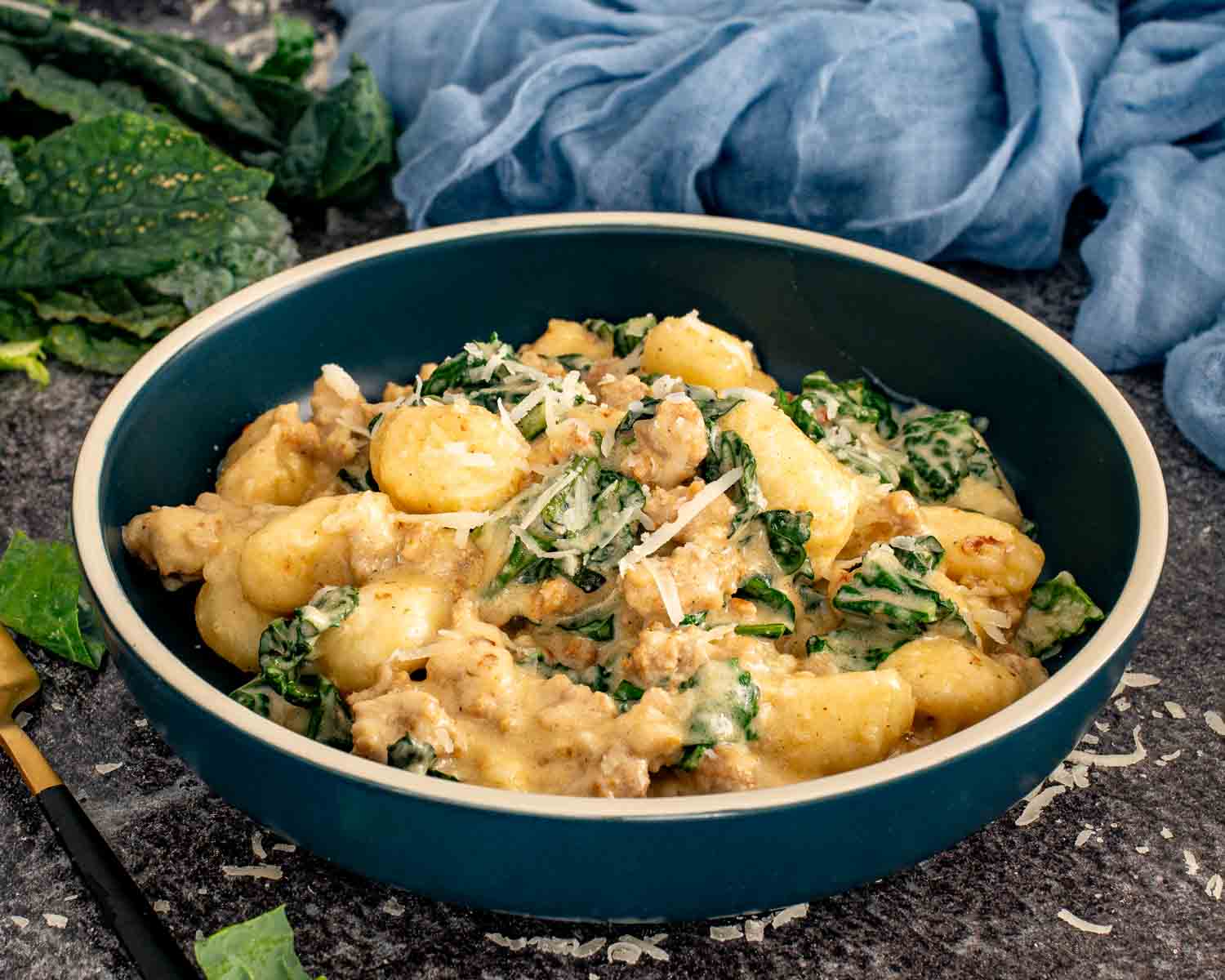 Bowl of creamy gnocchi with sausage and kale topped with grated Parmesan and served with a spoon. 4. Slightly wider bowl shot