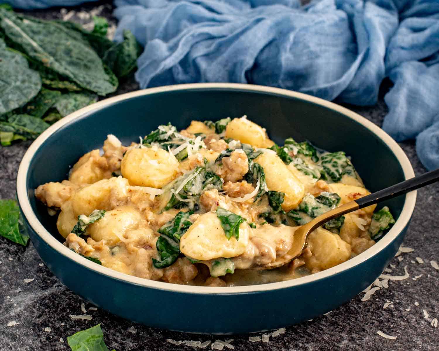 Bowl of creamy gnocchi with sausage and kale topped with grated Parmesan and served with a spoon. 4. Slightly wider bowl shot