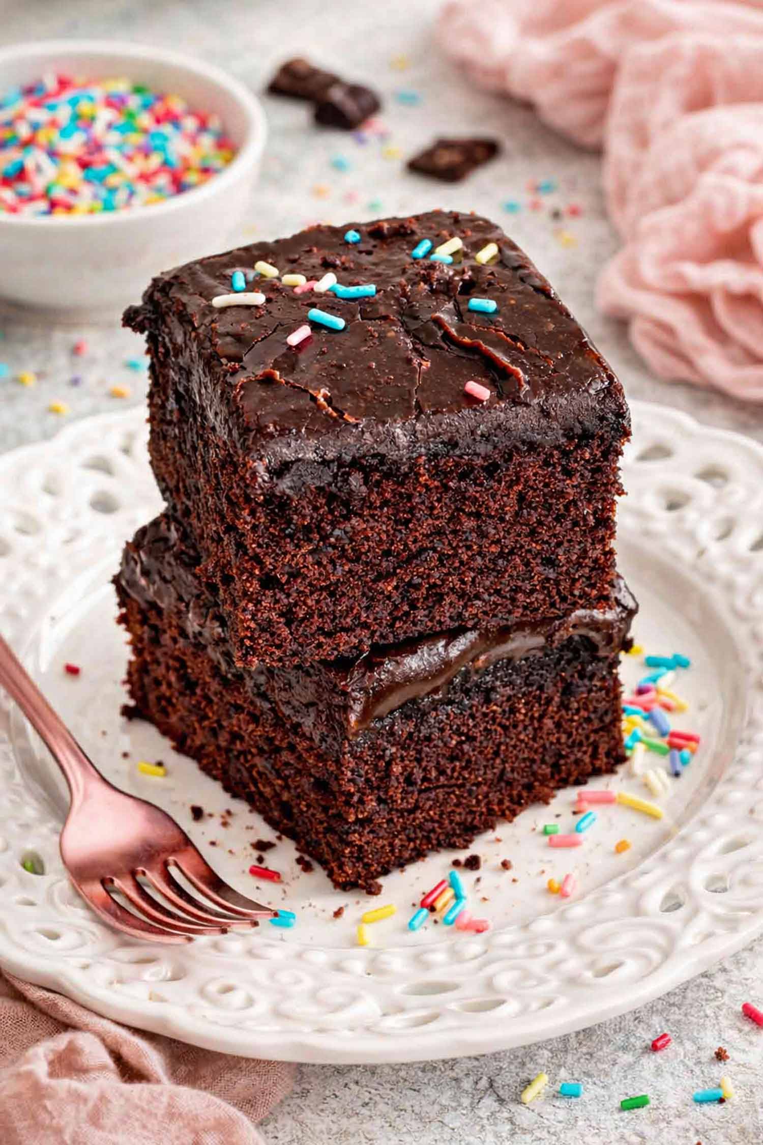 Stacked lunch lady brownies with thick chocolate frosting layer, soft moist crumb visible, served on decorative plate with colorful sprinkles.