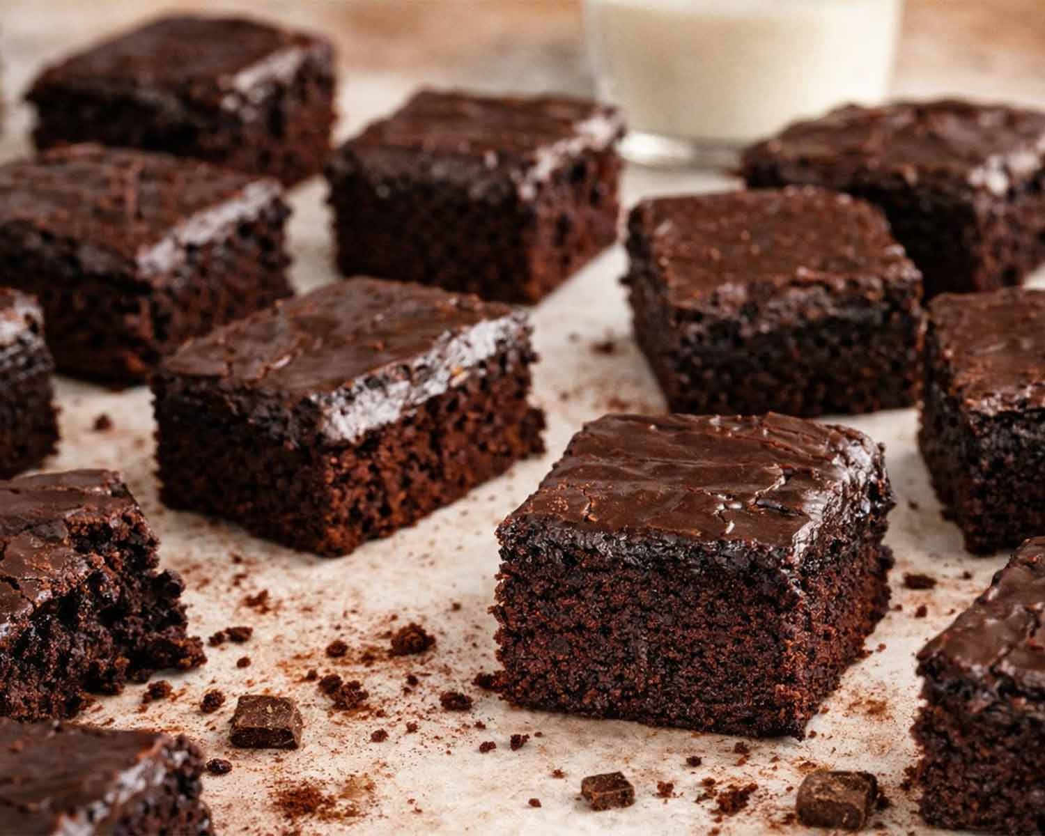 Lunch lady brownies cut into even squares with glossy chocolate frosting, soft fudgy centers and moist crumb displayed on parchment surface.