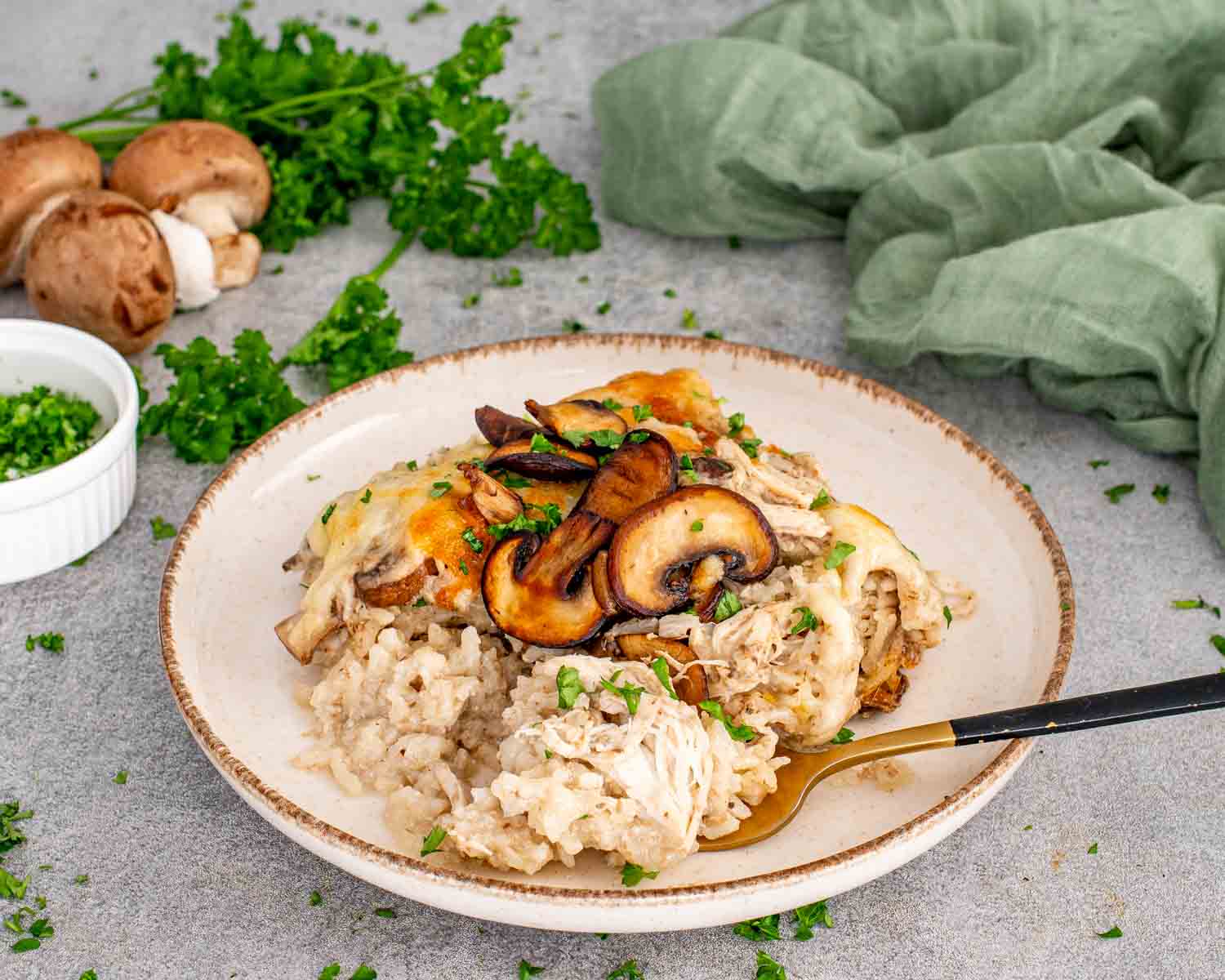 Serving of chicken and mushroom rice bake on plate with creamy rice, shredded chicken, saut&eacute;ed mushrooms, and melted cheese topping.