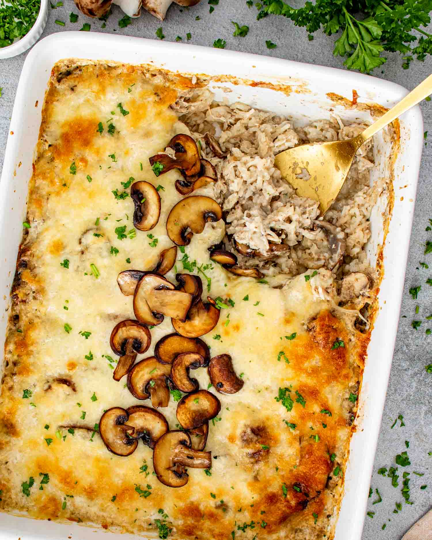 hicken mushroom rice bake scooped from casserole dish showing creamy rice texture, shredded chicken, melted cheese, and golden browned edges.